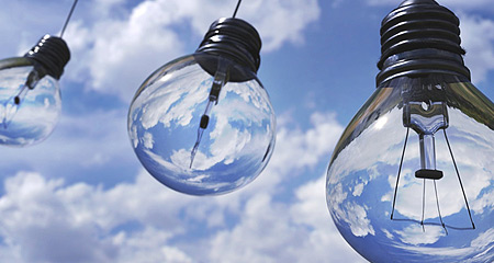 Light bulbs against a blue sky with puffy clouds.